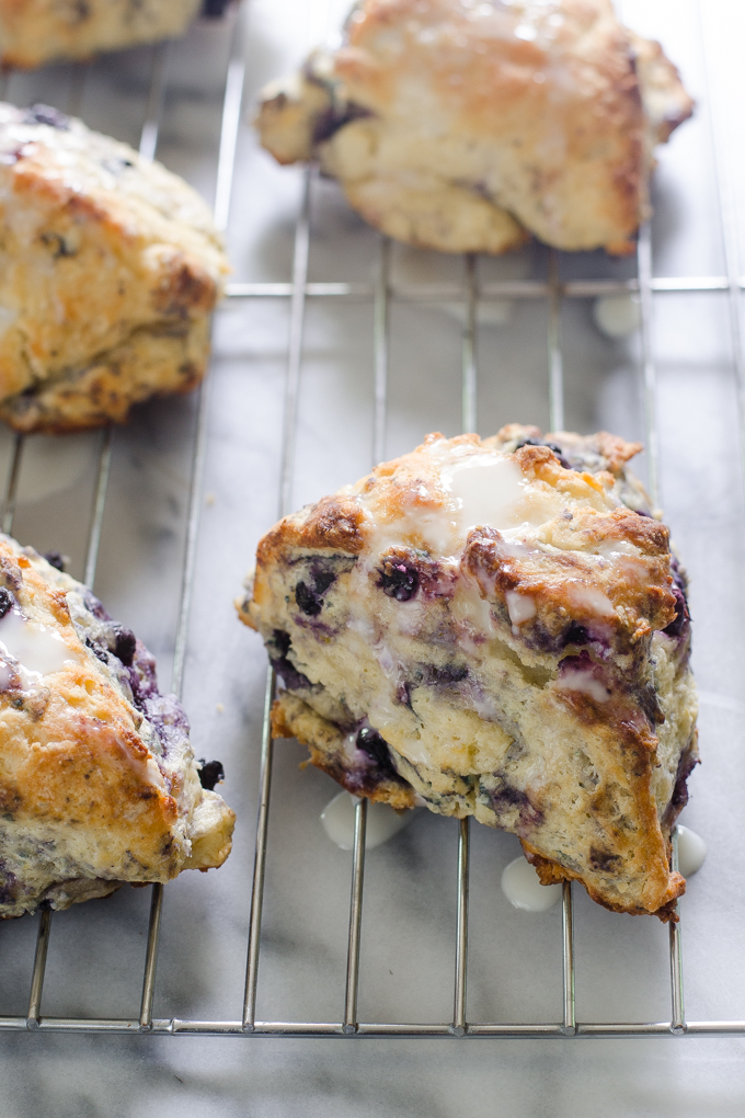 Blueberry Scones on a cooling rack drizzled with a Greek yogurt lemon glaze.