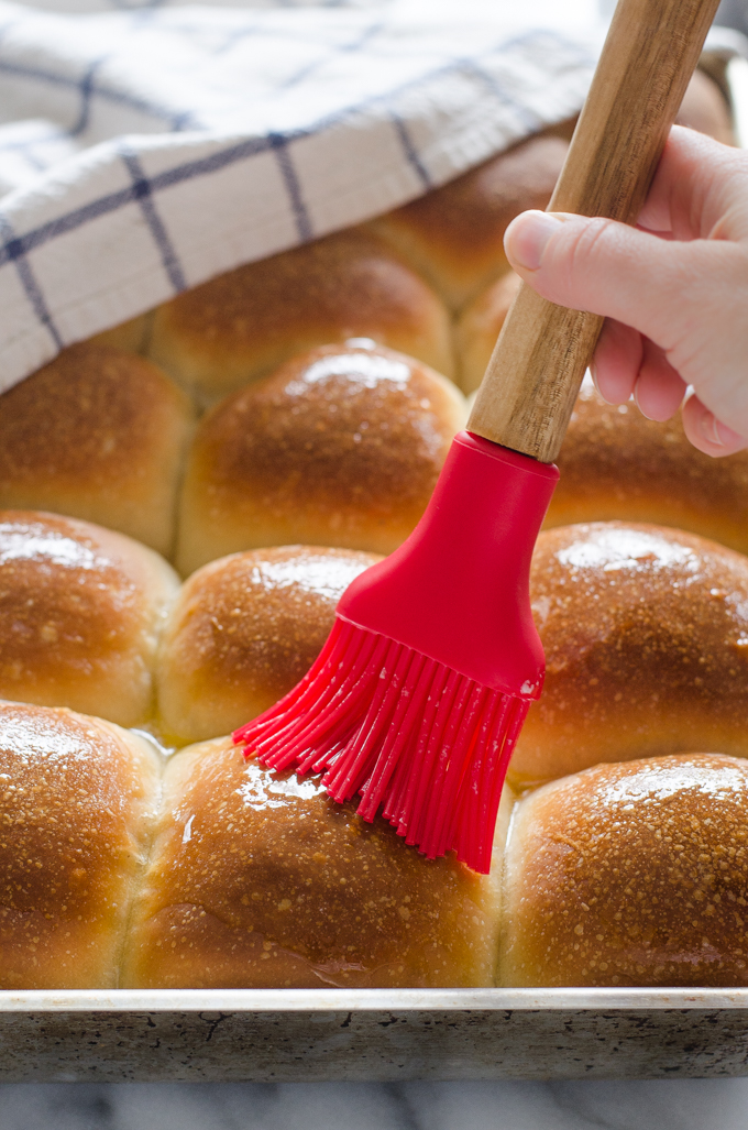 Brushing Sourdough Pull Apart Rolls with melted butter.