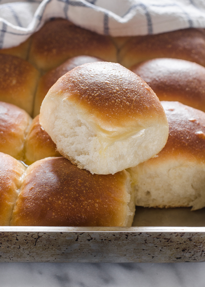 One sourdough roll on top of the rest of the pan of rolls.