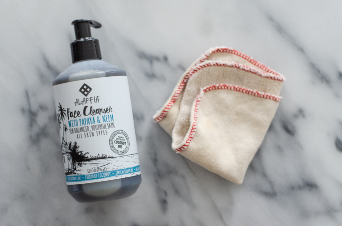 Alaffia face cleanser and organic face wash cloth on a marble surface.