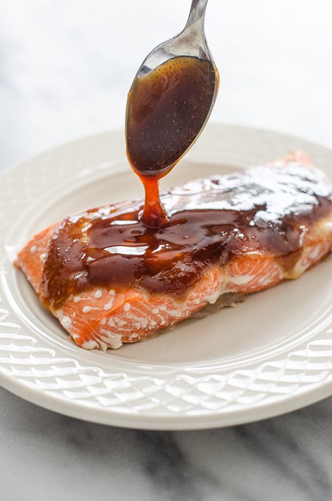 Drizzling homemade teriyaki sauce on a fillet of salmon.