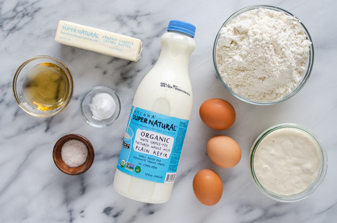 All of the ingredients for sourdough pancakes laid out on a marble surface.