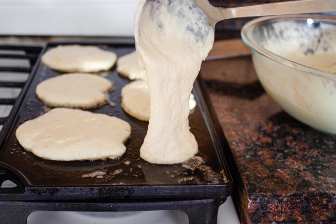 Ladling the sourdough pancake batter onto a hot griddle.