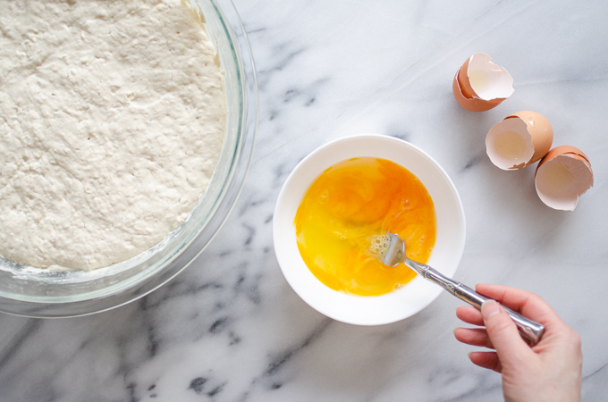 Lightly whisking the eggs in small bowl on a marble surface.