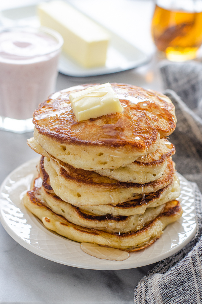 A stack of sourdough pancakes with a pat of butter and maple syrup dripping off the sides.