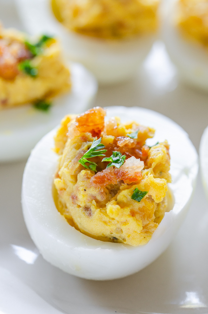 Close up shot of deviled eggs with bacon and parsley.