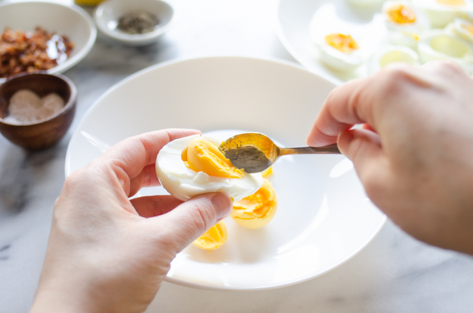 Scooping the yolks out for deviled eggs with bacon.