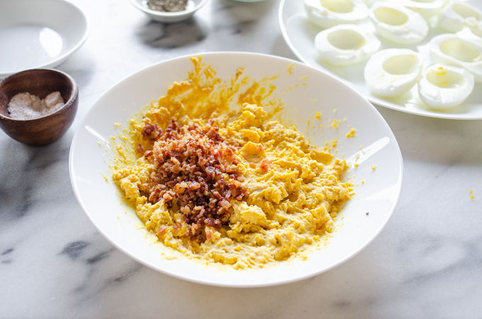 Adding the bacon to the deviled eggs filling mixture.