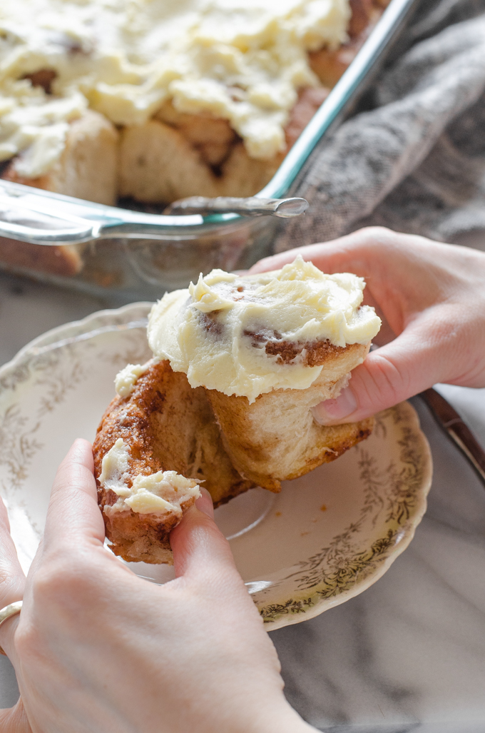 Pulling apart a sourdough cinnamon roll with cream cheese icing on top.