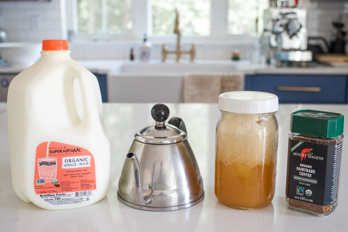 Milk, a tea kettle, honey, and instant coffee on a countertop.