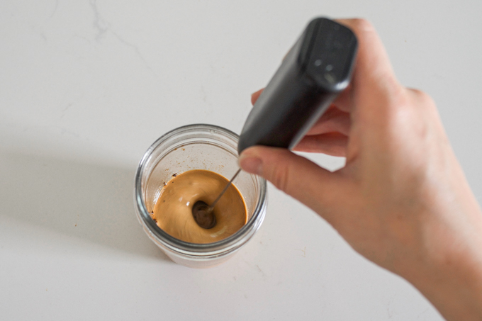 Whipping healthy Dalgona coffee with honey using a handheld frother.