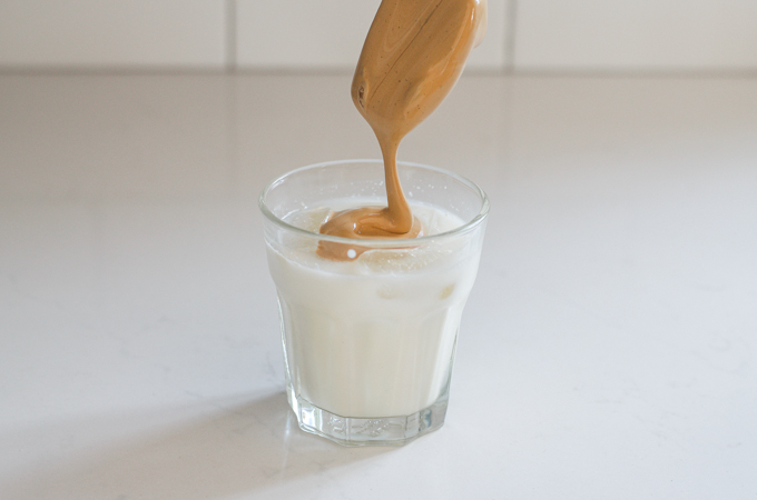 Scooping the whipped coffee over the glass of milk.