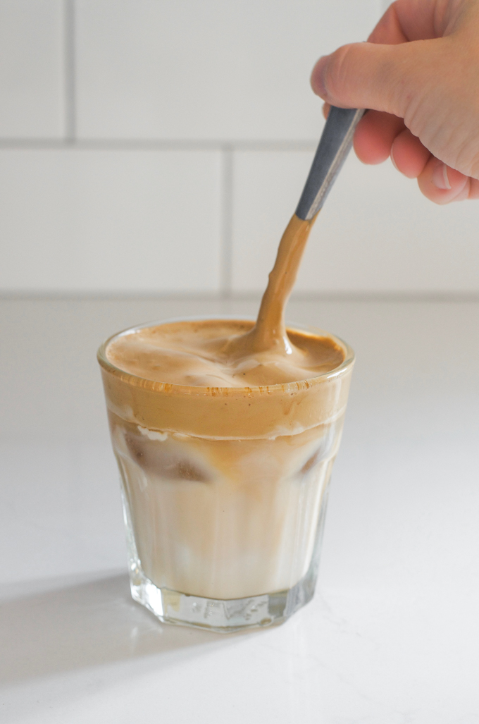 Stirring the whipped coffee with a spoon.