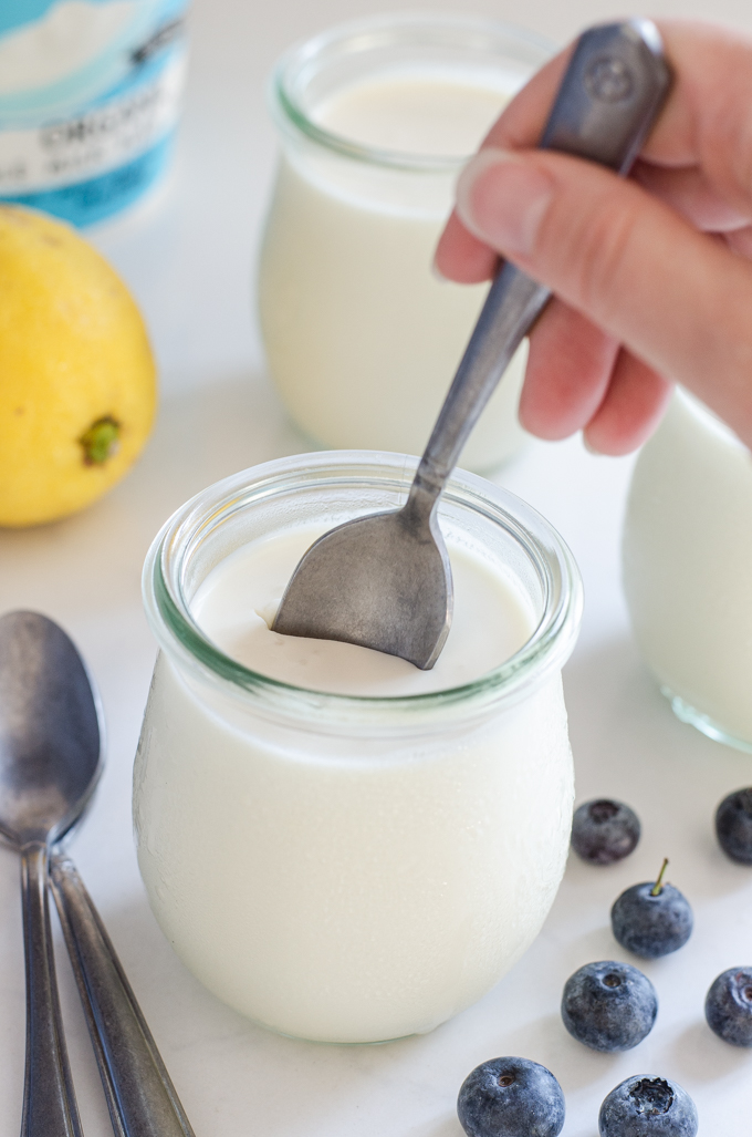 Dipping a spoon into a jar of yogurt panna cotta.