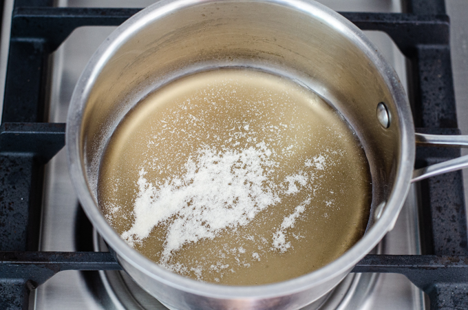 Sprinkling the gelatin over the maple syrup in a saucepan.