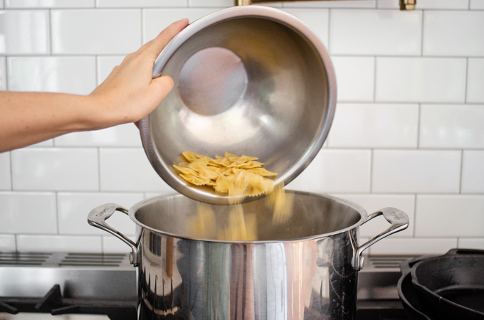 Adding the pasta to the boiling water.