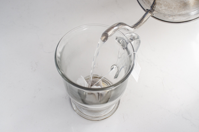 Pouring boiling water on top of the chai tea bag in the mug.