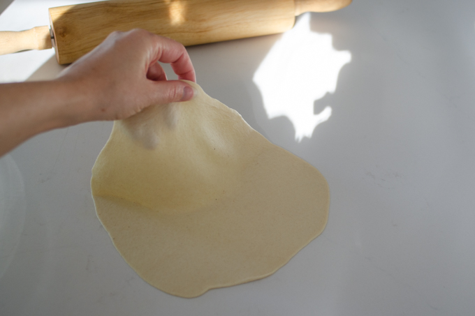 Pulling the rolled tortilla off of the counter.