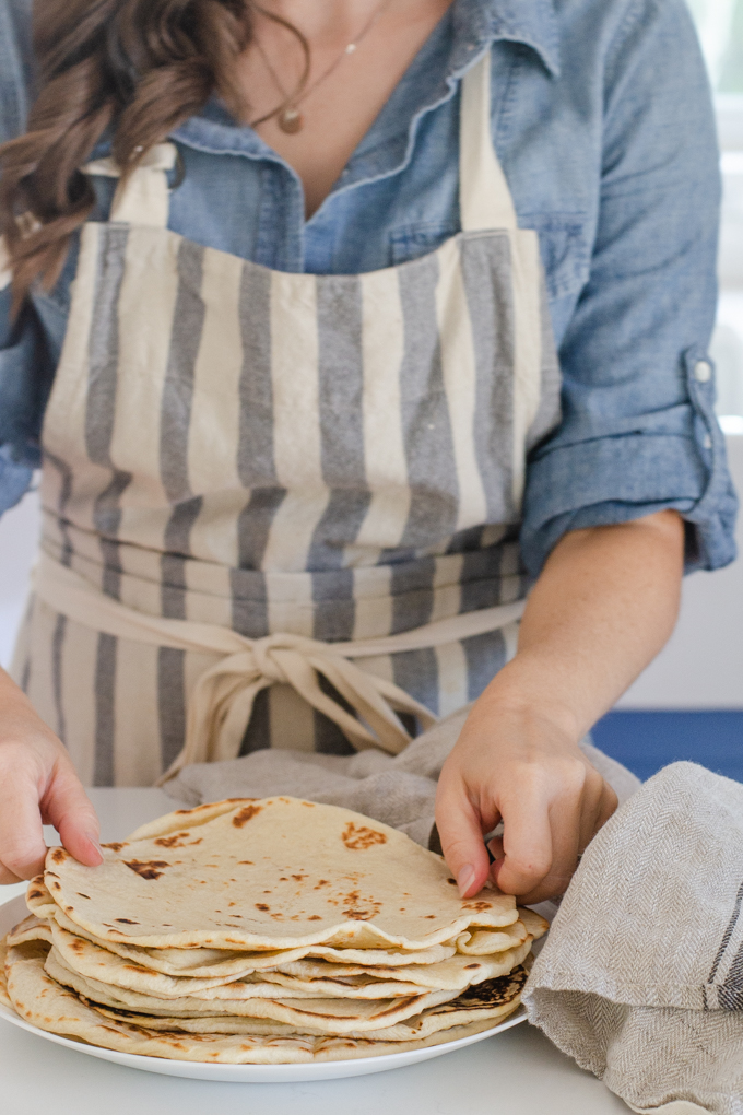 Placing the sourdough tortillas on a plate.