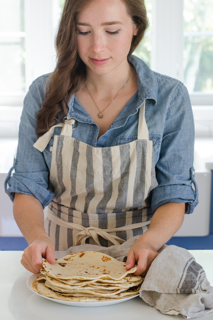 Placing the sourdough tortillas on a plate.