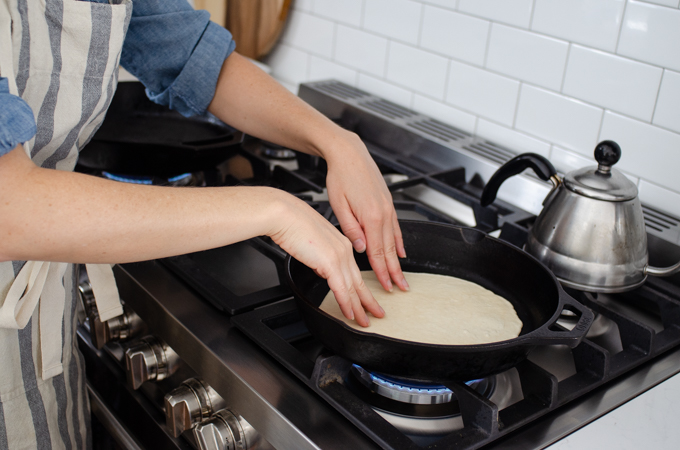 Placing the rolled tortilla in a hot cast iron skillet.