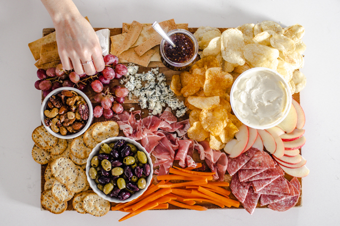 Adding the grapes, carrots, and apples to the snack board.