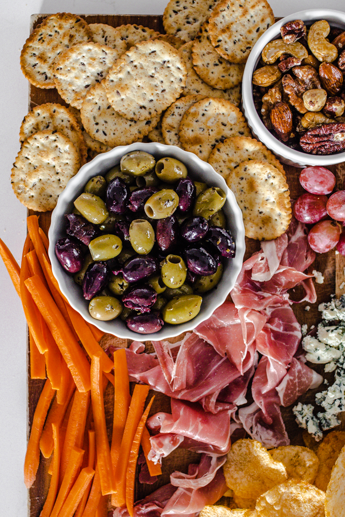 Olives, crackers, roasted nuts, grapes, prosciutto, blue cheese, chips, and carrots.