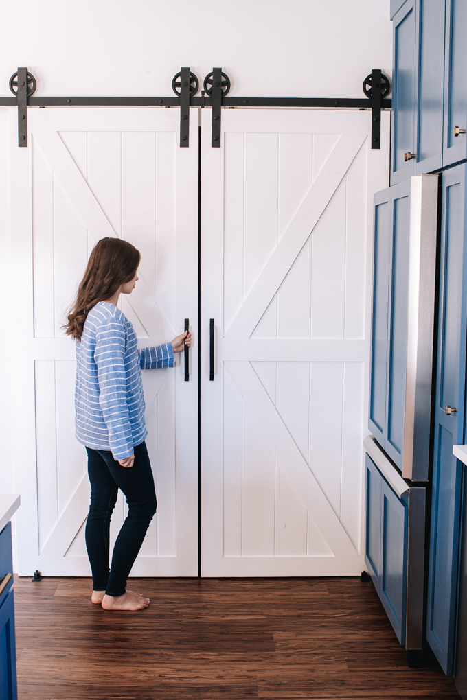 Sliding barn door pantry next to fridge in a transitional modern farmhouse kitchen.