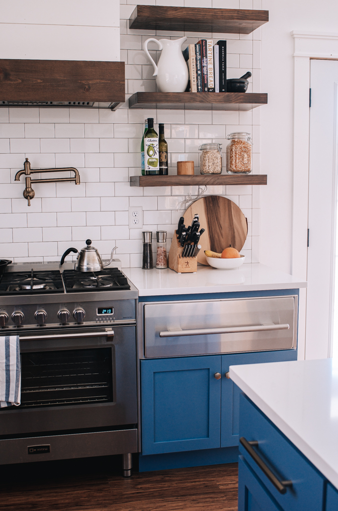 Open shelving in a transitional kitchen with subway tile backsplash up to the ceiling. 