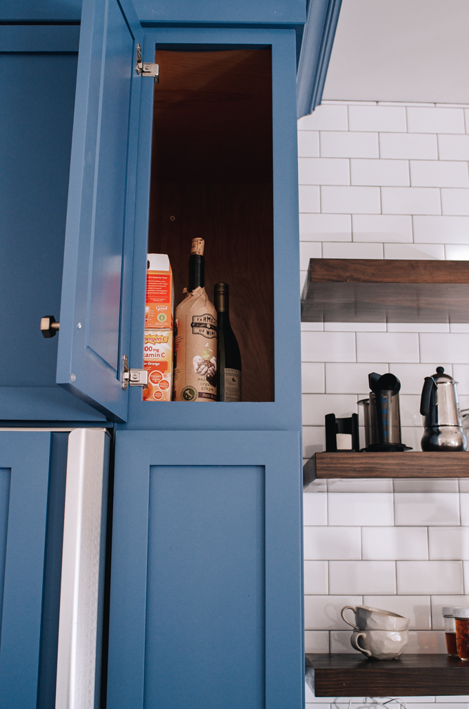 Blue transitional kitchen cabinets next to refrigerator. 