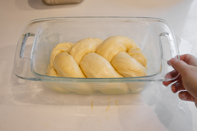 Tucking the sourdough brioche braid into the greased loaf pan.