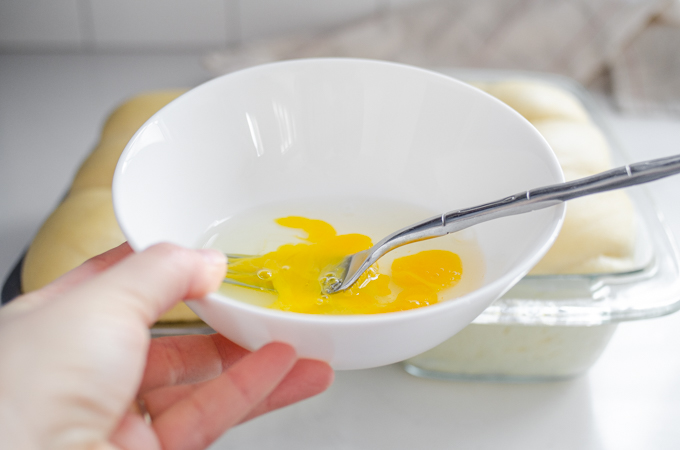 Whisking together an egg plus a tablespoon of water to brush on top of the loaf.