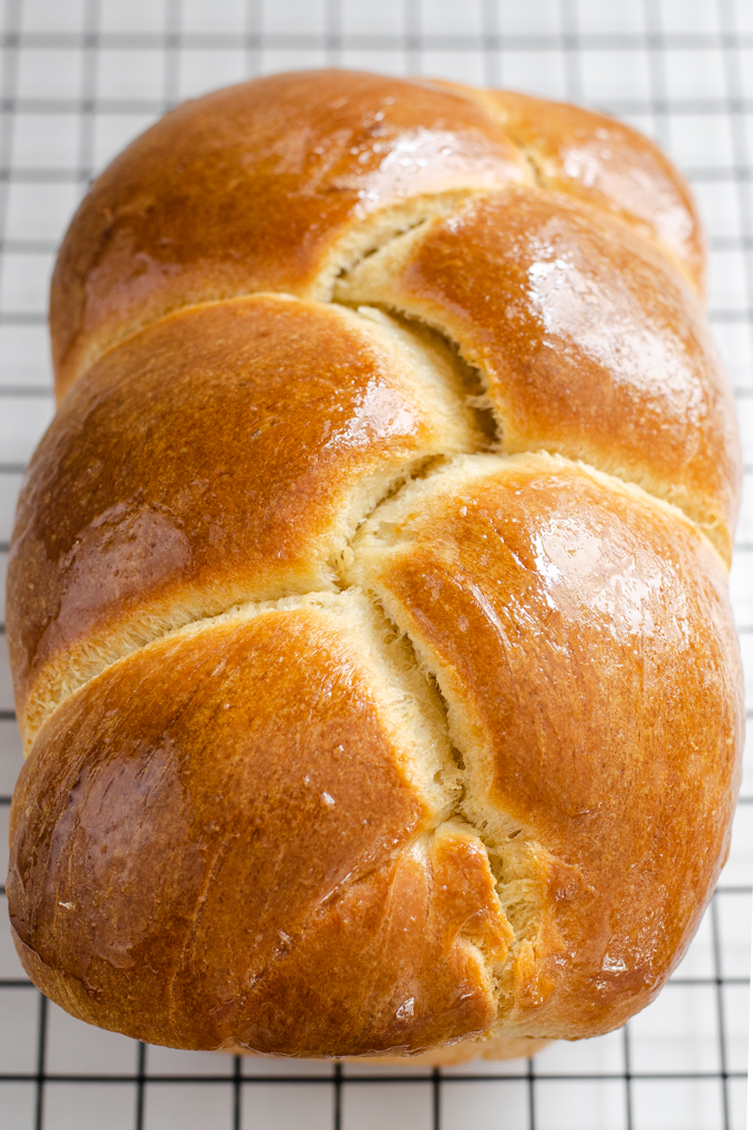 A loaf of sourdough brioche bread on a black wire cooling rack.