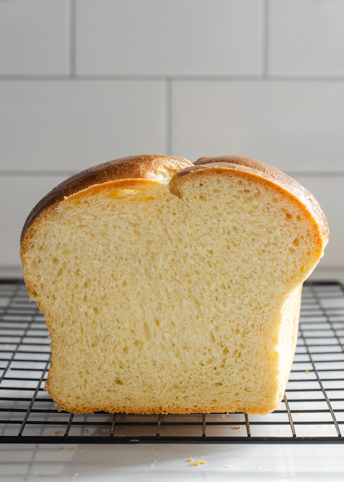 A side view of a loaf of sourdough brioche bread with a slice taken out.
