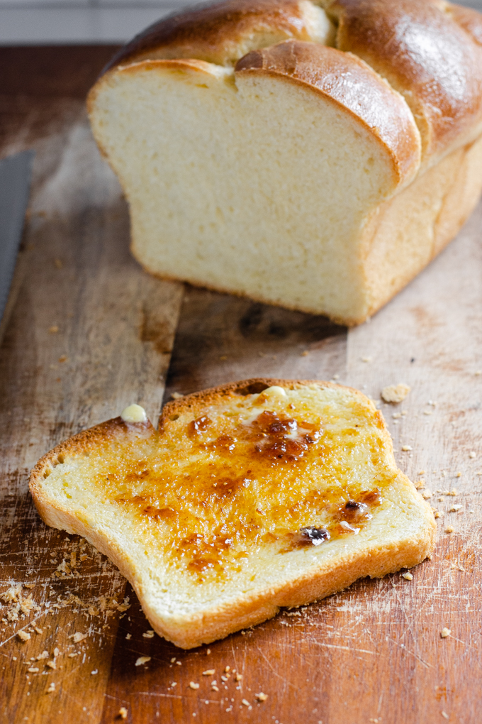 A toasted slice of sourdough brioche bread with melted butter and fig jam.