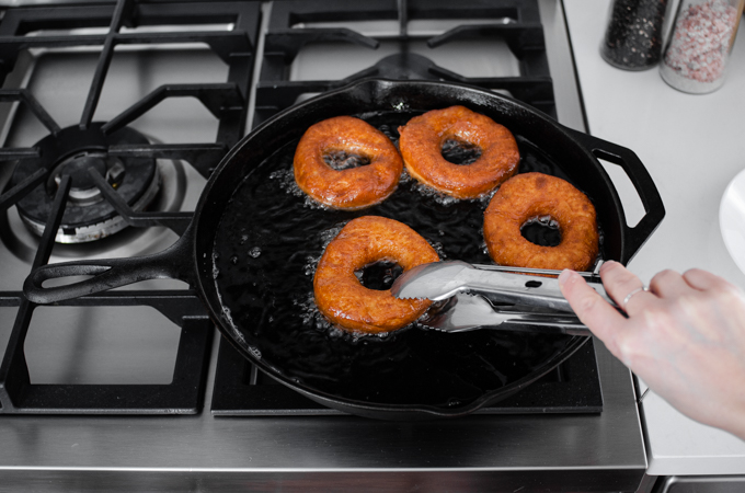 Flipping the doughnuts while they fry.