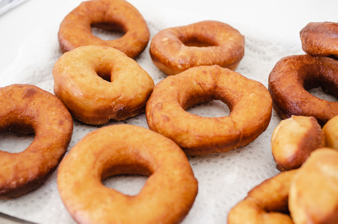 The fried sourdough donuts on a paper towel lined baking sheet.