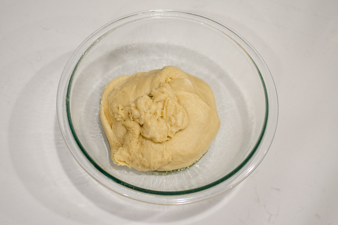 Placing the dough for this sourdough donut recipe in a greased bowl.