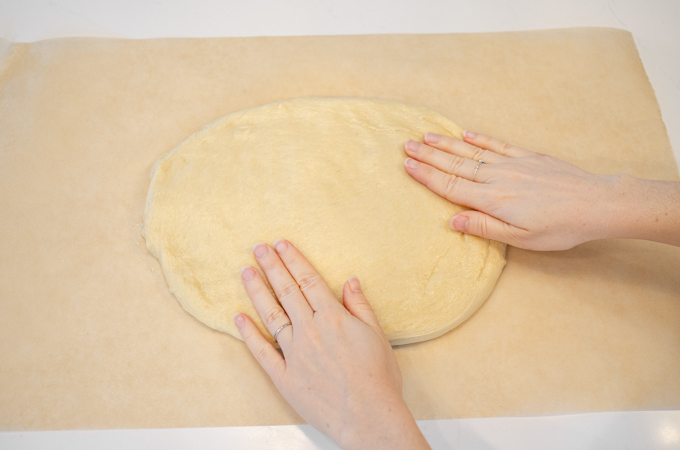 Patting the dough out on a piece of parchment paper.