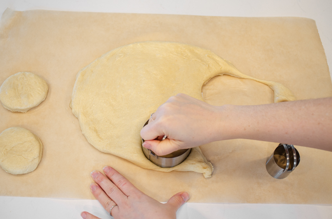 Cutting out rounds of dough with a biscuit cutter.