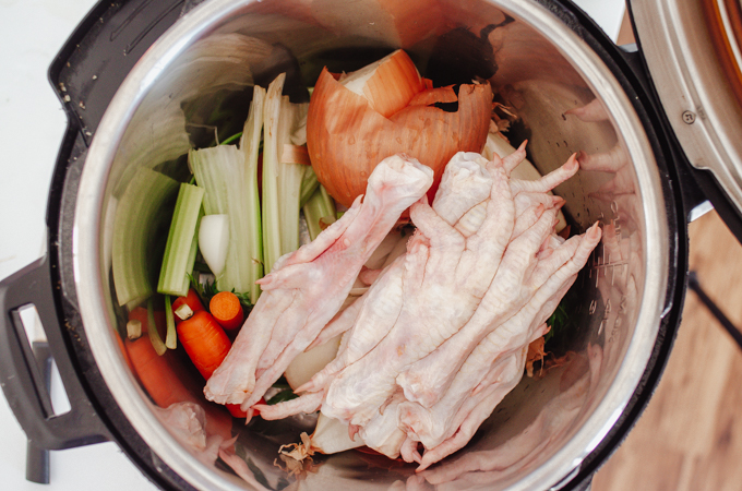Placing ingredients for the chicken feet bone broth in the Instant Pot.