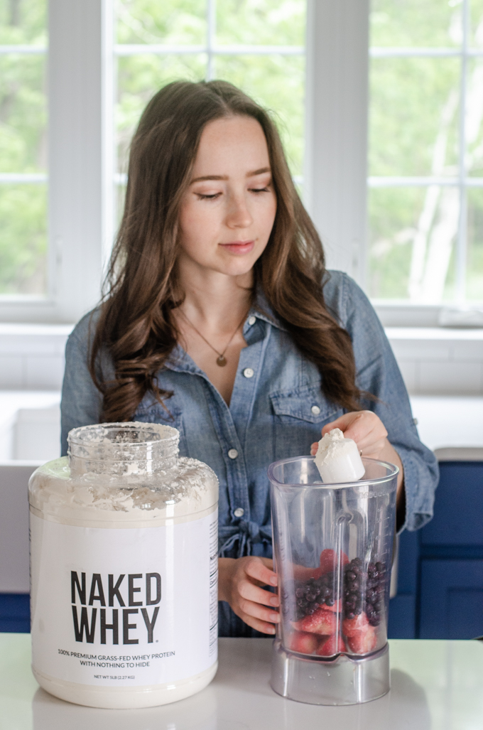 Adding a scoop into a blender to make a smoothie. 