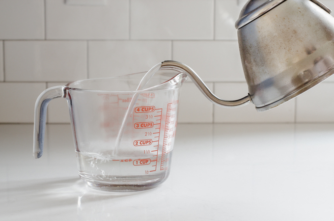 Pouring boiling water into a glass measuring cup.